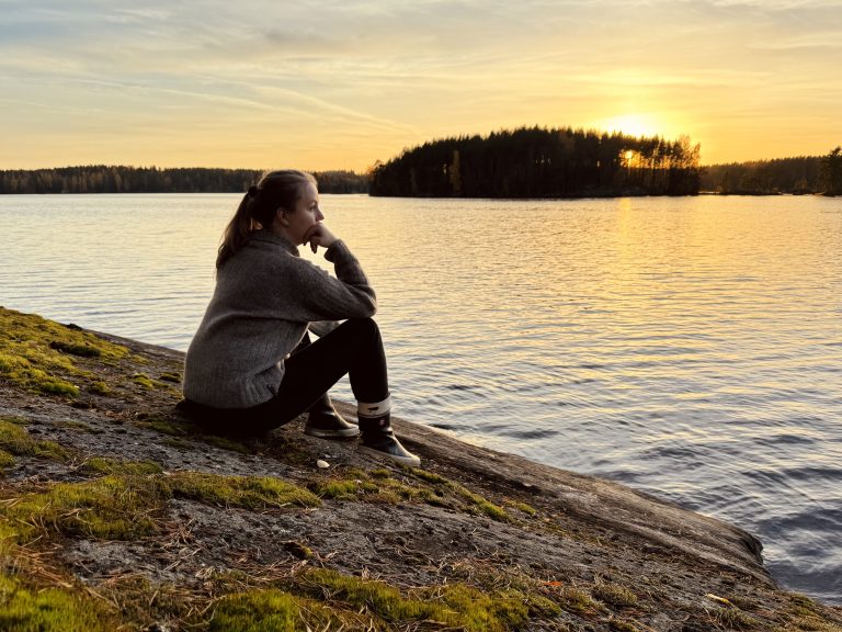 Laura Hautsalo katselee auringonlaskua rannalla
